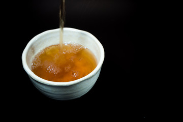 Tea in ceramic cup on black background