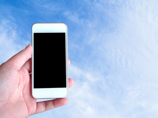 Left-hand holds the smartphone grey screen with sky background behind