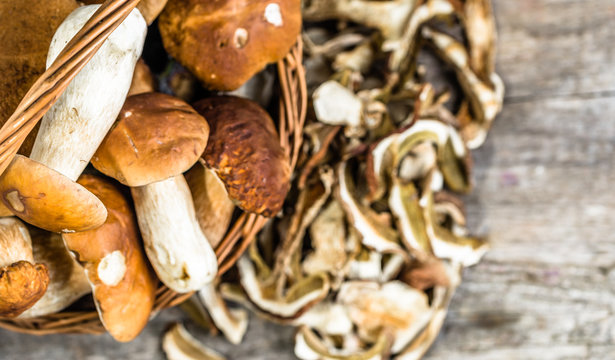 Fresh boletus mushrooms in a basket and dried mushrooms on woode