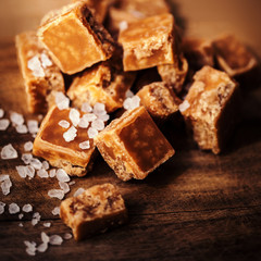 Caramel candies on brown background. Salted caramel pieces and s