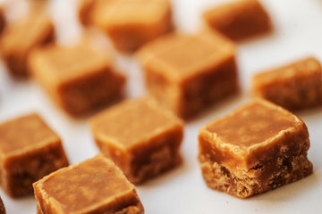 Caramel candies on brown background. Salted caramel pieces and s
