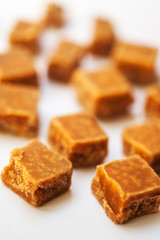 Caramel candies on brown background. Salted caramel pieces and s