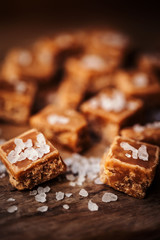 Caramel candies on brown background. Salted caramel pieces and s