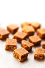Caramel candies on brown background. Salted caramel pieces and s