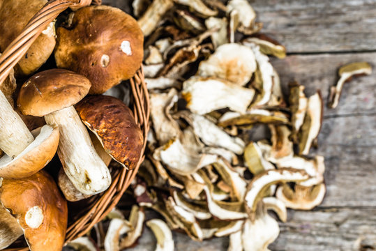 Fresh boletus mushrooms in a basket and dried mushrooms on woode