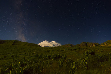Snowy mountain Elbrus in moonlight, Milky Way stars and Saturn at night