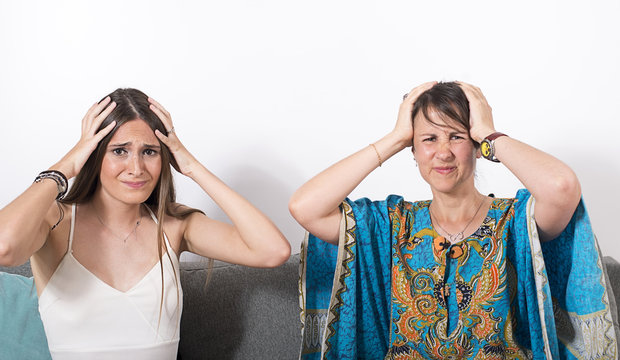 Portrait of two young brunette girls holding their head because of headache