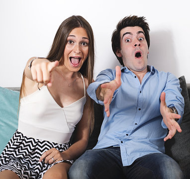 Portrait of toothy smiling man and brunette woman showing thumbs up at camera indoor. Surprise