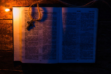 Bible and cross next to candles selective focus
