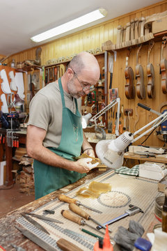 Violin maker working on new instrument in his workshop