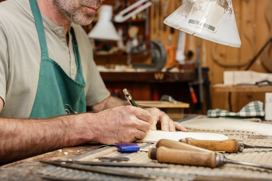 Cut wood and gauges on workbench of violin maker