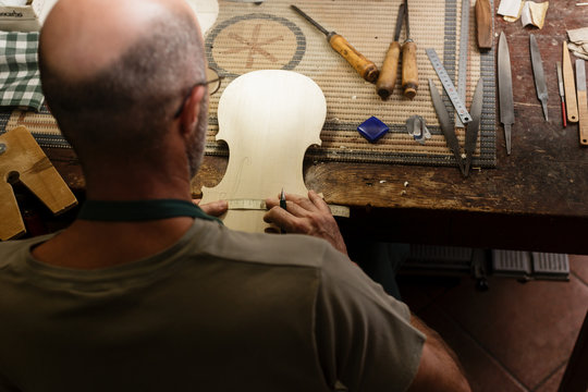Instrument maker platting cut marks on wood for new violin