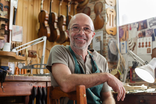 Violin maker in his workshop looking satisfied