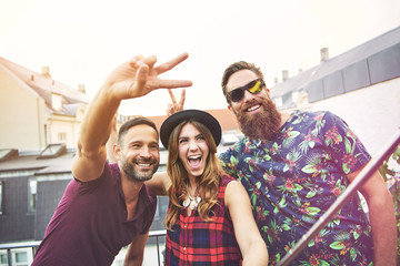 Man makes peace sign beside two smiling friends