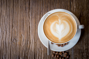 cup of art latte coffee on wood table background