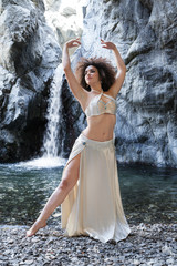 giovane donna in abito bianco danza con cascata sullo sfondo