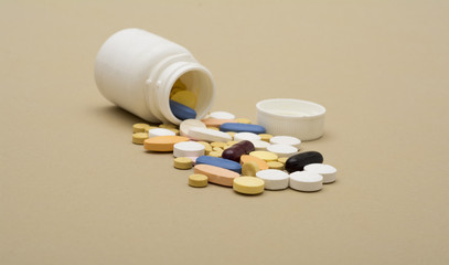 colorful pills of medicine coming out from a plastic drug bottle