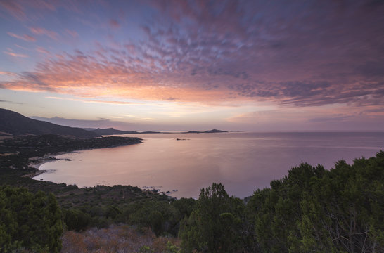 The colors of sunrise are reflected on the sea around the beach of Solanas, Villasimius, Cagliari, Sardinia, Mediterranean