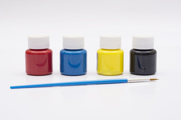 Four paint bottles in prime colors with painting brush