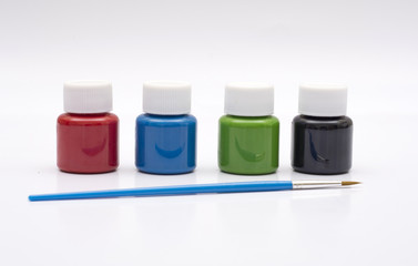 Four paint bottles in prime colors with painting brush