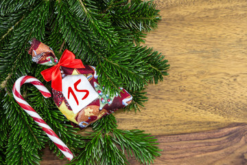 ein Weihnachtssäckchen und eine Zuckerstange liegen auf Tannenzweigen