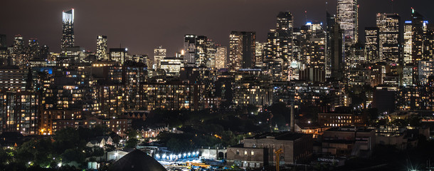 Fototapeta premium Urban lighted landscape and skyline of Toronto. A rooftop panoramic of urban streets, homes, condos, and office towers on a hot, humid August night in The capitol of Ontario, Canada,