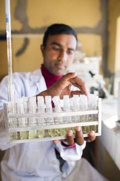A lab technician working in a laboratory in a small hospital in Nepal holds a rack of test tubes, Jiri, Solu Khumbu, Nepal