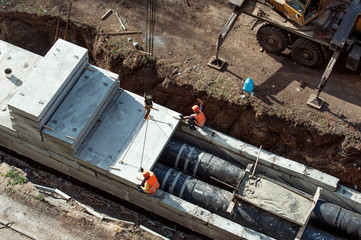 Workers constructing a trench for main heating with a concrete elements and a cement