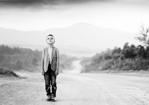 boy standing on a dusty road black and white photography