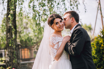 Bride and groom in a park kissing.couple newlyweds bride and groom at a wedding in nature green forest are kissing photo portrait.Wedding Couple