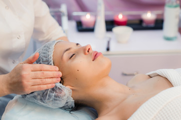 Beautiful young woman relaxing with face massage at beauty spa