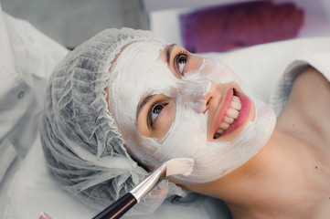 Young woman at spa procedures applying mask