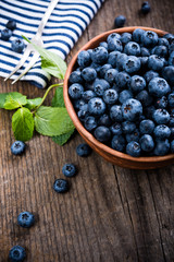 Full bowl of fresh ripe blueberries on old wooden board
