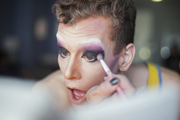 Close up of young man applying drag makeup
