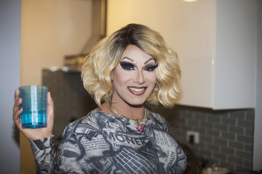 Portrait of smiling drag queen holding a glass