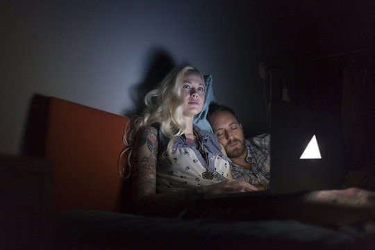 Young couple looking at a laptop in bed
