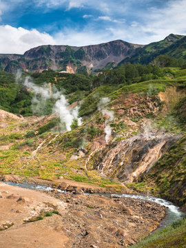 Toned image Geyser Valley with the river flowing at the bottom against the backdrop of huge volcano on Kamchatka in Russia