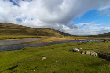 Beautiful scenery in Scotland. River flows through a green valley. Green mountainside in the background.