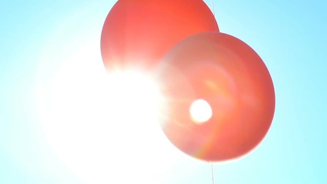 Bright red balloons in the sun. Slow motion.