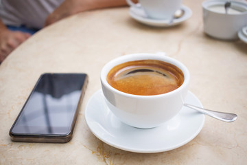 Phone and cup of coffee on marble table