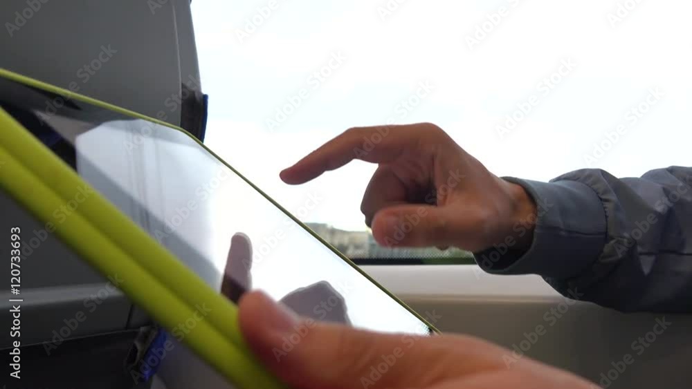 Poster man's hand tapping touchscreen of tablet computer in the train. 4k close up shot
