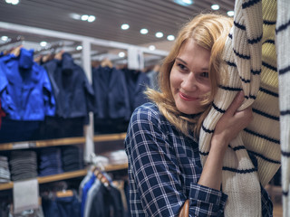 Attractive girl in a boutique fashion embraces soft cardigan.