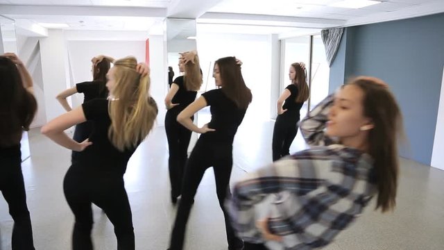 Girls in black uniform actively dance in class on lesson of choreography