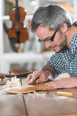 Craftman luthier working on the creation of a violin at workshop