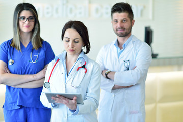 healthcare and medicine concept - attractive male doctor in front of medical group in hospital showing thumbs up