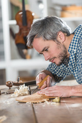 Craftman luthier working on the creation of a violin at workshop