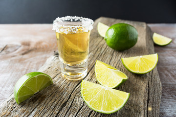 Tequila shot with lime on rustic wooden background