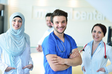 healthcare and medicine concept - attractive male doctor in front of medical group in hospital...