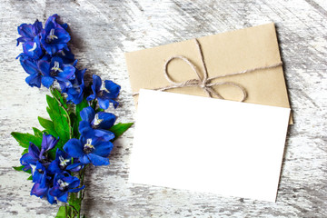 Blank white greeting card and envelope with blue wildflowers. holiday background