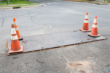 Metal plate covering a hole with four orange cones